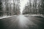 zdjecie zaśnieżonej drogi asfaltowej w lesie