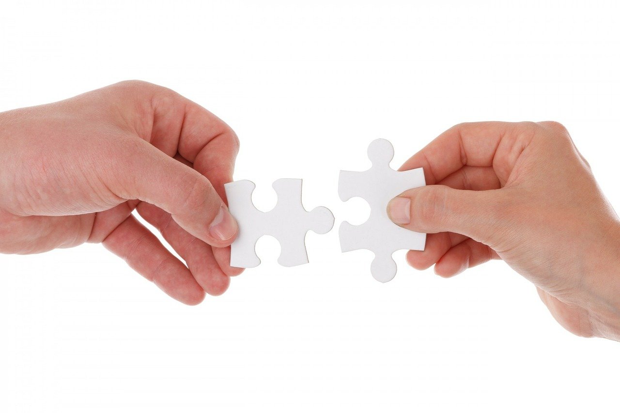 Dłonie układajce białe puzzle