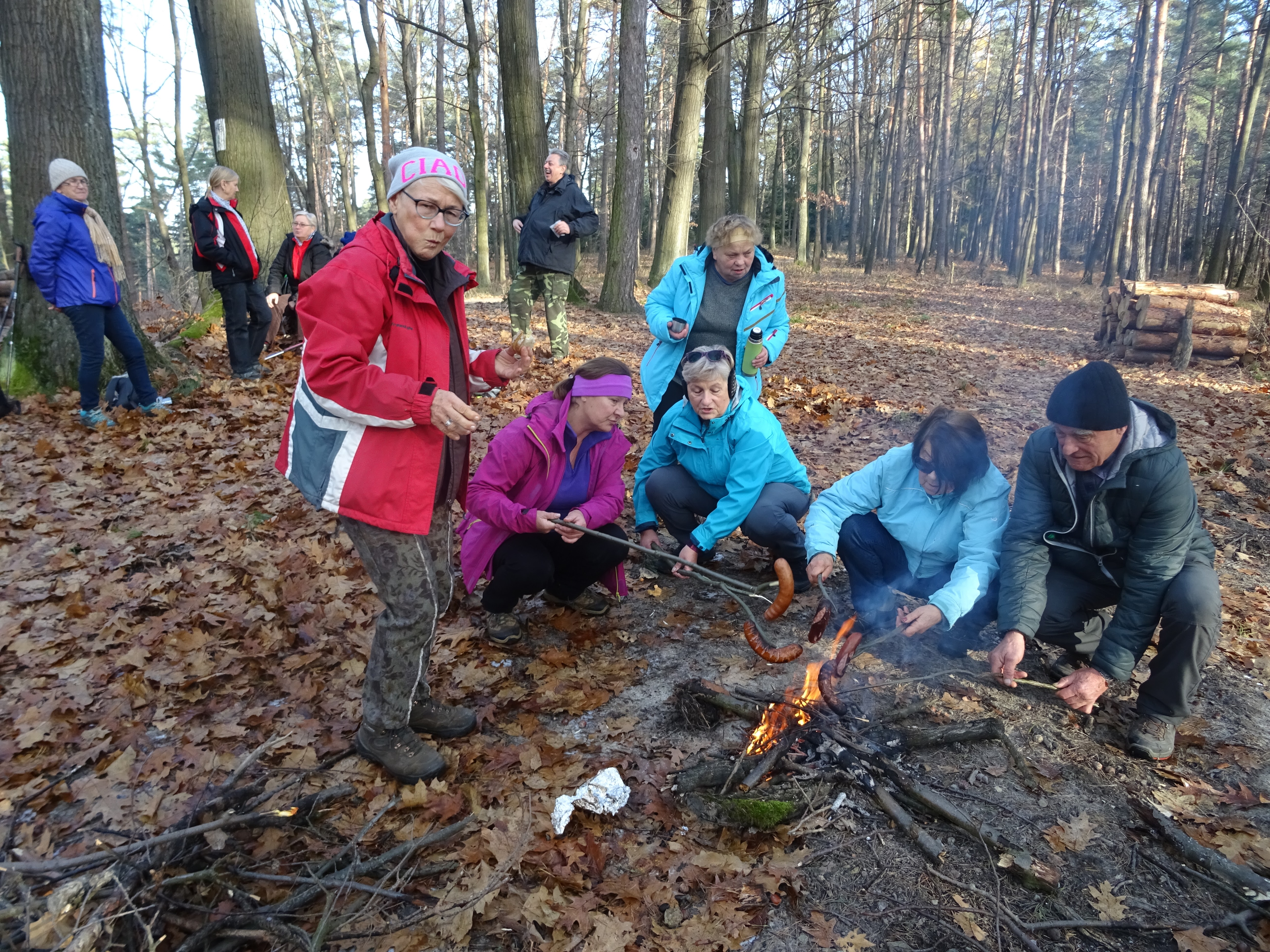 grupa osób w lesie rozpalająca ognisko.