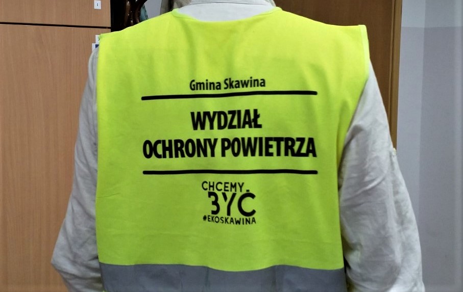 Zdjęcie osoby w kamizelce z napisami: Gmina Skawina, Wydział Ochrony Powietrza, Chcemy być #ekoSkawina